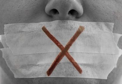 Close-up of face with tape over mouth and cross drawn on it