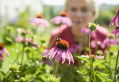 A woman looking at a bee on a flower