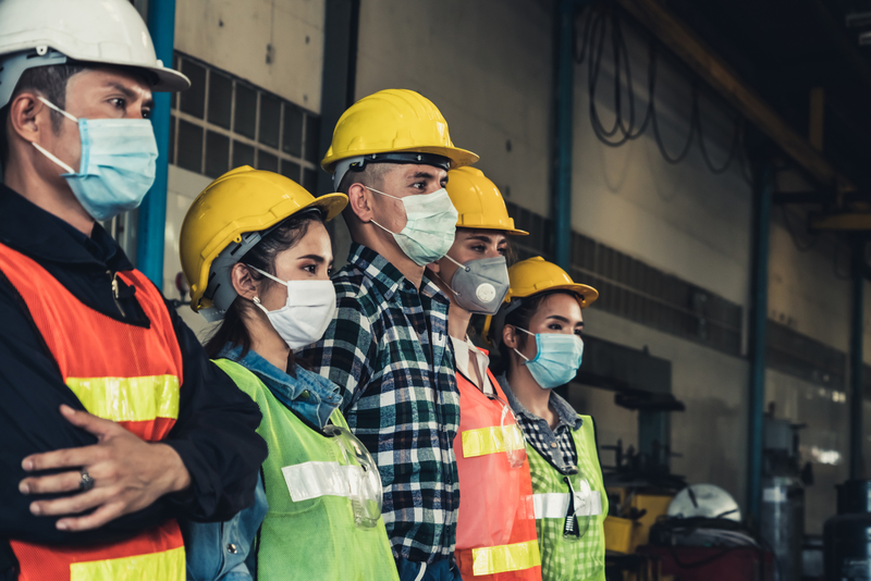 The image shows a line of workers wearing medical masks to protect themselves from coronavirus.