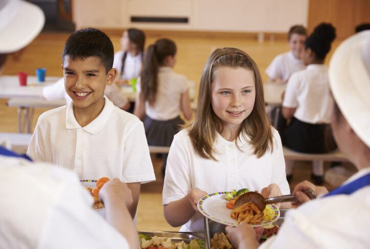 Two children in school uniform are given their school lunch