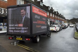 An image of an advertising van with a picture of Chancellor Jeremy Hunt on the back, and the phrase "What are you going to do about it Chancellor?"