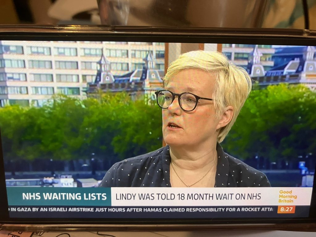 A screenshot of Good Morning Britain news coverage, a woman speaking under the caption 'NHS waiting lists, Lindy was told 18 months on the NHS'