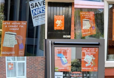 A collage of different windows from different homes, all with orange posters in them reading "a chance for change"